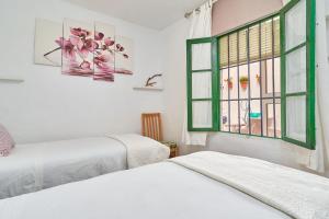 two beds in a room with a window at Casa Victoria G in Nerja