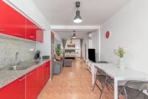 a kitchen with red cabinets and a living room at Vv Ancla in Puerto de Mogán
