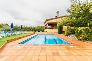a swimming pool with chairs and a house at Rural Mas Vila in Fogás de Tordera