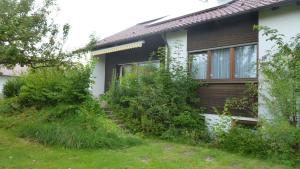 a house with weeds growing around the side of it at Ferienhaus Unteres Hart in Gomadingen