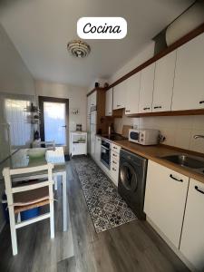 a kitchen with white cabinets and a table and a dishwasher at Amets in Yesa
