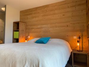 a bedroom with a white bed with a wooden wall at Flambeaux A 12 Roca immobilier in Châtel