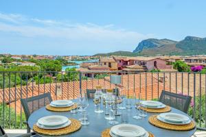 a table with plates and glasses on a balcony at Villa Mirtina - by And Service in Golfo Aranci