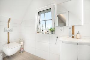 a white bathroom with a toilet and a window at Haus Ankerplatz in Wischhafen +30 photos