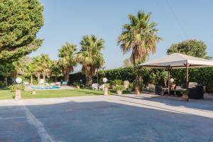 a patio with a tent and a park with palm trees at Casa Margiulu’ - Partanna in Partanna