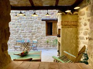 a patio with a table and chairs and a stone wall at La Casuca in Olba