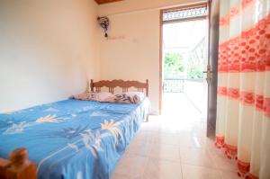 a bedroom with a bed with a blue comforter at Villa Ransanda in Warakagoda