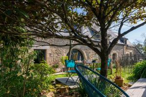 a patio with two blue chairs under a tree at La Longère d'Arzoù Chambres D'hôtes in Baden