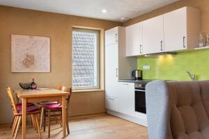 a kitchen with a table and chairs and a kitchen with green tiles at Bio Bausewein - No.1 Apartment in Iphofen