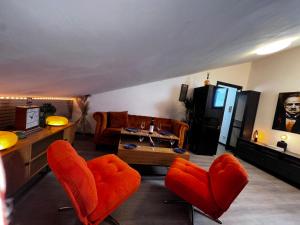 a living room with orange chairs and a couch at Nice and cozy apprtment in Murazzano with panoramic view in Murazzano