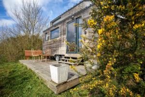 a tiny house sitting on a deck with a table and chairs at Très Jolie Tiny House Tout Confort in Prat