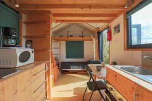 a tiny house with a kitchen and a bunk bed at Très Jolie Tiny House Tout Confort in Prat +14 photos