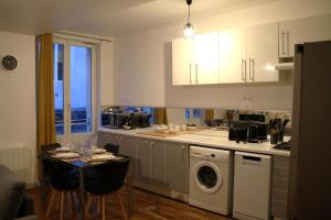 a kitchen with a washing machine and a table with chairs at La Parenthèse Saint-Etienne- Nevers in Nevers