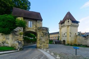 an old stone building with an arch and a castle at La Parenthèse Saint-Etienne- Nevers in Nevers
