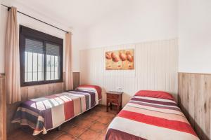 two beds in a room with a window at Chalet El Cancelín in Conil de la Frontera +15 photos