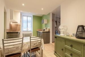 a kitchen with green walls and a table and chairs at Appartement T2 Les Pyrénées in Bagnères-de-Bigorre