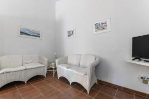 a living room with two chairs and a flat screen tv at Appartamento La Spiga in Procchio
