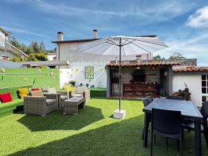 a patio with a table and an umbrella on a lawn at Refugio Senhora Paz in Marinhas