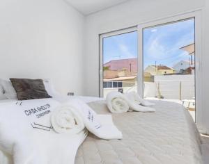 a bedroom with a large white bed with a large window at Casa da Madou in Setúbal
