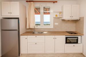 a kitchen with white cabinets and a stainless steel refrigerator at Anemologio 201 Tinos in Agios Ioannis