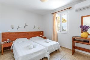 a bedroom with two beds and a window at Anemologio 201 Tinos in Agios Ioannis