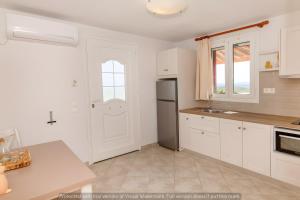 a kitchen with white cabinets and a refrigerator at Anemologio 201 Tinos in Agios Ioannis