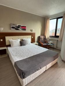 a bedroom with a large bed and a chair at Private Rooms Trakiets in Pomorie