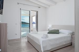 a white bedroom with a bed and a view of the ocean at Villa Cormorani 1 in Golfo Aranci