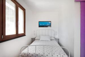a white bed in a room with a tv on the wall at Monolocale Fattorialmare Viola in Camogli