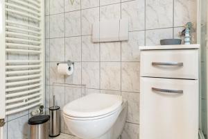 a bathroom with a white toilet and a white tiled wall at Ferienwohnung Schatzlmayr in Vilshofen an der Donau +14 photos