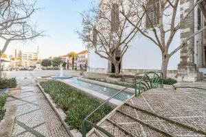 a fountain in the middle of a street with trees at Duplexdubocage in Setúbal