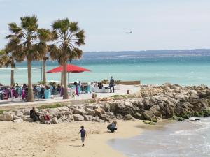 a child walking on a beach with a group of people at Palma Townhouse Near the Beach in Palma de Mallorca