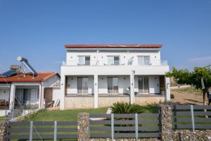 a white house with a fence in front of it at Sunset View House In Chalkidiki in Nea Potidaea