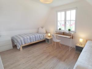 a white bedroom with a bed and a desk at Haus Elve in Zierow