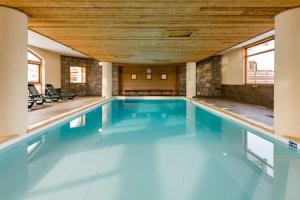 a large swimming pool with a wooden ceiling at Duplex confortable avec piscine in La Toussuire