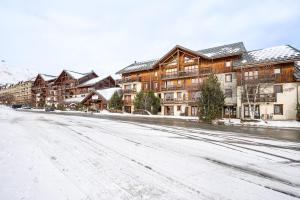 a snow covered street in a town with buildings at Duplex confortable avec piscine in La Toussuire