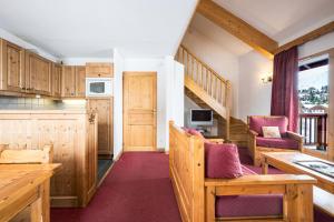 a kitchen with wooden cabinets and chairs and a staircase at Duplex confortable avec piscine in La Toussuire