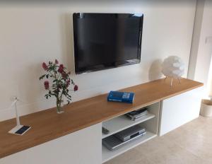 a television on a wall with a vase of flowers at Apartamento Llenaire in Pollença