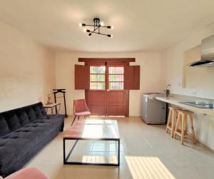 a living room with a black couch and a kitchen at Casa Colibri Central Villa with Private Pool and Tub Merida in Mérida