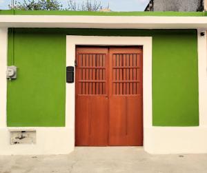 a green and white building with a wooden door at Casa Colibri Central Villa with Private Pool and Tub Merida in Mérida
