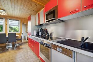a kitchen with red cabinets and a counter top at Ferienhaus 249 - Haus Seeblick in Zadelsdorf +5 photos