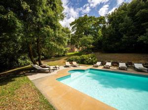 a swimming pool with chaises and chairs next to some trees at Fattoria La Striscia in Gambassi Terme