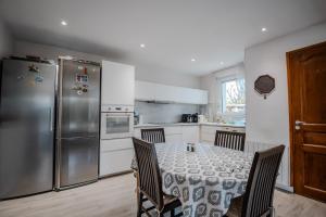 a kitchen with a table and a stainless steel refrigerator at Chambre Armand in Louvigny