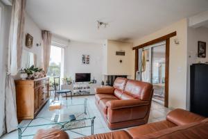 a living room with a leather couch and a television at Chambre Armand in Louvigny