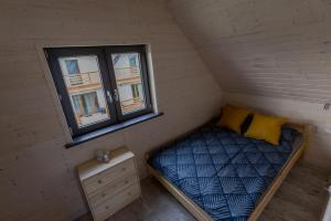 a small bed in a room with a window at Domki u Bazyla in Sarbinowo