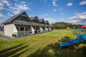 a row of houses with a playground in the yard at Domki u Bazyla in Sarbinowo