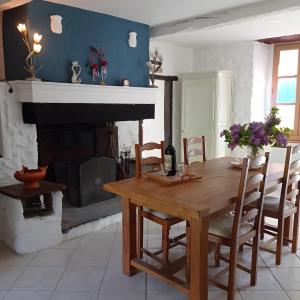 a dining room with a wooden table and a fireplace at Maison Typique De Montagne in Ercé