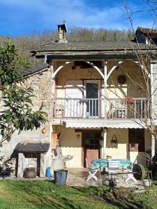 a house with a balcony and a table on a patio at Maison Typique De Montagne in Ercé