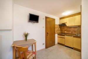 a kitchen with a table and a tv on the wall at Rieglhof Apartment Hennennest in Curon Venosta +18 photos