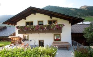 a house with a balcony with flowers on it at Rieglhof Apartment Hennennest in Curon Venosta